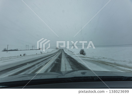 Snowy road stretches ahead through winter landscape in cold weather Snowy road stretches ahead through winter landscape in cold weather 138023699