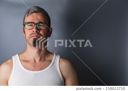 Man with glasses and goatee stands against a gray backdrop 138023710