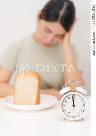hungry woman with whole wheat bread and clock. concept of intermittent fasting, IF, meal, Time to eat, choosing healthy carbohydrates, balanced diet and weight loss management, Nutrition schedule hungry woman with whole wheat bread and clock. concept of intermittent fasting, IF, meal, Time to eat, choosing healthy carbohydrates, balanced diet and weight loss management, Nutrition schedule 138023850