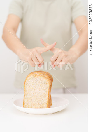 Unhappy woman showing Rejecting gesture and refusing to eat bread. concept of gluten intolerance, gluten sensitivity, carb loading concerns, or a disliking for unhealthy dietary habits 138023858