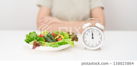 happy smiling woman with fresh organic vegetables plate and alarm clock. intermittent fasting, IF, meal time, nutrition, weight loss, clean eating, Healthy food eating, Wellness, dieting and lifestyle 138023864