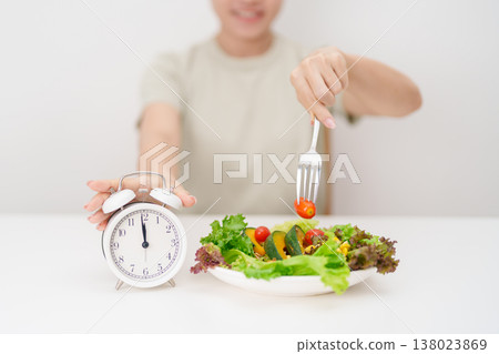 happy smiling woman with fresh organic vegetables plate and alarm clock. intermittent fasting, IF, meal time, nutrition, weight loss, clean eating, Healthy food eating, Wellness, dieting and lifestyle happy smiling woman with fresh organic vegetables plate and alarm clock. intermittent fasting, IF, meal time, nutrition, weight loss, clean eating, Healthy food eating, Wellness, dieting and lifestyle 138023869