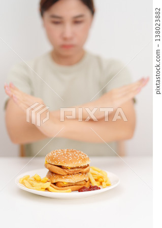 Unhappy woman showing Rejecting and refusing with Juicy beef burger, potato chips and carbonated Soft drinks. Unhealthy, High calorie, Fast food craving, Obesity, diet, weight loss and junk food Unhappy woman showing Rejecting and refusing with Juicy beef burger, potato chips and carbonated Soft drinks. Unhealthy, High calorie, Fast food craving, Obesity, diet, weight loss and junk food 138023882