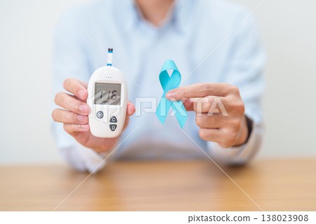 Hand show Blue Ribbon and digital blood glucose meter with lancet pen. high blood sugar level, November World Diabetes Day, Awareness month, Glycemia,, Hyperglycemia and insulin testing and checking Hand show Blue Ribbon and digital blood glucose meter with lancet pen. high blood sugar level, November World Diabetes Day, Awareness month, Glycemia,, Hyperglycemia and insulin testing and checking 138023908