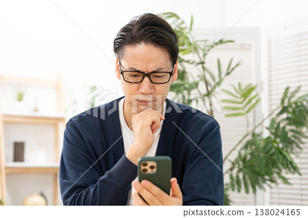 A man is troubled while looking at his smartphone; he is shocked. 138024165