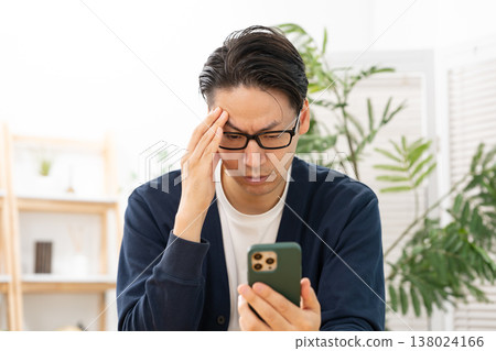 A man is troubled while looking at his smartphone; he is shocked. 138024166