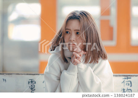 Portrait of a woman in her 20s sitting on a train station bench. Portrait of a woman in her 20s sitting on a train station bench. 138024187