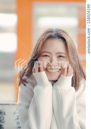 Portrait of a woman in her 20s sitting on a train station bench. Portrait of a woman in her 20s sitting on a train station bench. 138024190