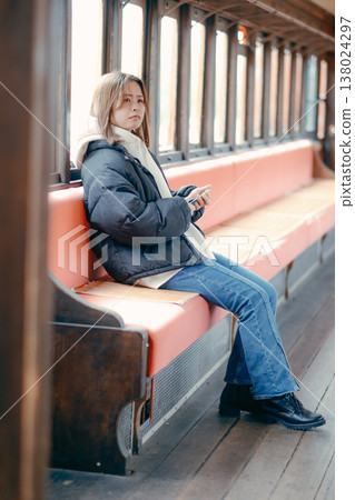 Portrait of a woman in her 20s using her smartphone on a train. Portrait of a woman in her 20s using her smartphone on a train. 138024297