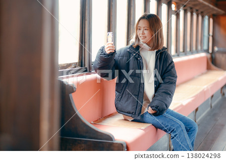 Portrait of a woman in her 20s using her smartphone on a train. 138024298