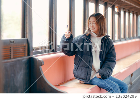 Portrait of a woman in her 20s using her smartphone on a train. 138024299
