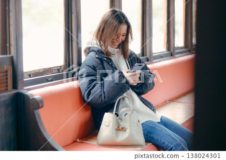 一位二十多歲的女性在火車上使用智慧型手機的肖像。 138024301