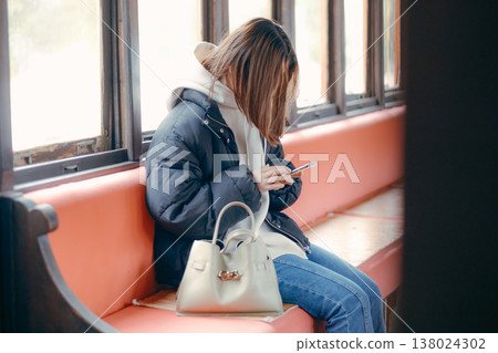 一位二十多歲的女性在火車上使用智慧型手機的肖像。 138024302