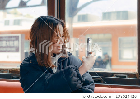 Portrait of a woman in her 20s using her smartphone on a train. Portrait of a woman in her 20s using her smartphone on a train. 138024426