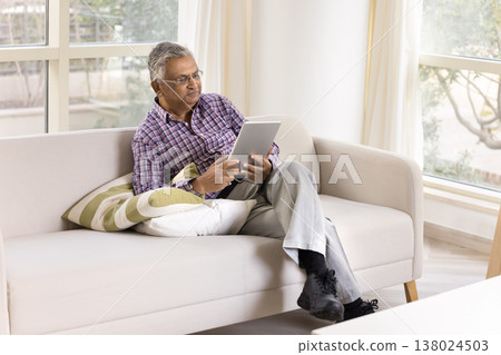 Focused old man dressed casually wear glasses using digital tablet Focused old man dressed casually wear glasses using digital tablet 138024503