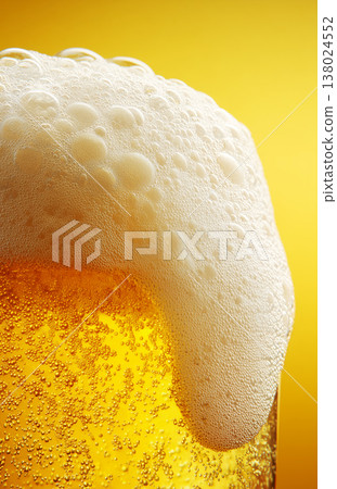 Fizzy beer glass with foam in closeup on warm golden background, concept of refreshment and celebration Fizzy beer glass with foam in closeup on warm golden background, concept of refreshment and celebration 138024552