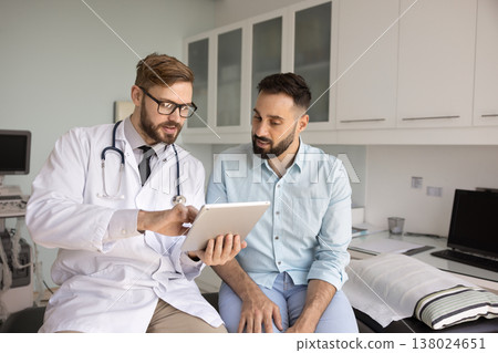 Male doctor discussing therapy plan with patient using electronic pad Male doctor discussing therapy plan with patient using electronic pad 138024651