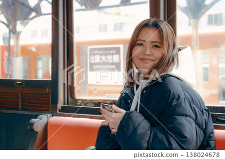 Portrait of a woman in her 20s waiting on a train with her bag in hand. 138024678