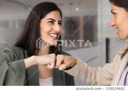 Two businesswomen giving friendly fist bump in modern office 138024682