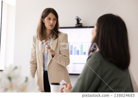 Confident businesswoman standing and speaking during meeting in modern office 138024683