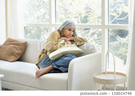 Woman curled up on couch, hugging pillow, suffers from loneliness 138024746