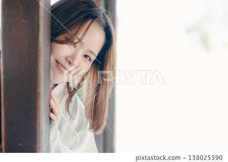 一位二十多歲的女子從一輛老式火車的車門裡探出頭來,臉上帶著微笑。 一位二十多歲的女子從一輛老式火車的車門裡探出頭來,臉上帶著微笑。 138025390