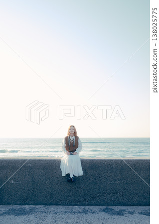 Portrait of a young woman holding a camera on the beach Portrait of a young woman holding a camera on the beach 138025775
