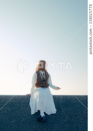 Portrait of a young woman holding a camera on the beach 138025778