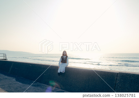 Portrait of a young woman holding a camera on the beach 138025781