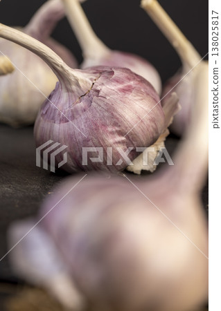 ripe purple garlic is scattered on a table in the kitchen, garlic spices are on a black slate board in the kitchen over cooking ripe purple garlic is scattered on a table in the kitchen, garlic spices are on a black slate board in the kitchen over cooking 138025817