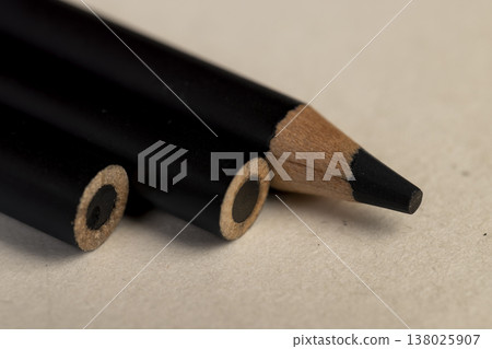 a row of black wooden pencils folded on cheap loose paper, wooden pencils with lead for drawing or other work 138025907