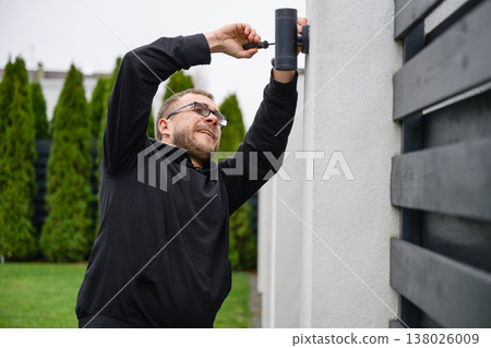 Man installing outdoor wall light with screwdriver Man installing outdoor wall light with screwdriver 138026009