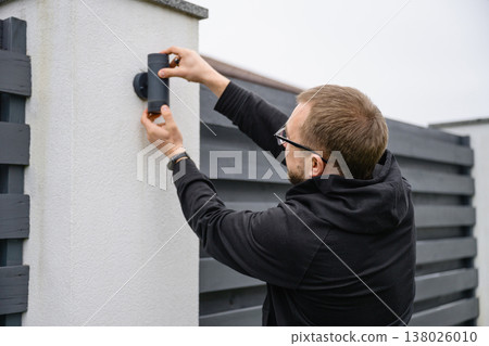 Man installing outdoor wall light with screwdriver Man installing outdoor wall light with screwdriver 138026010