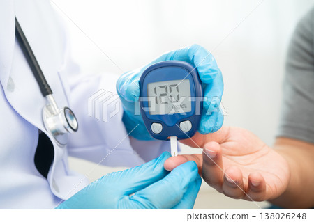 Asian doctor using digital glucose meter for check sample blood sugar level to treatment diabetes. 138026248