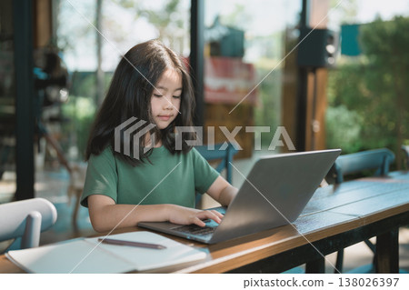 Young girl focused on laptop in modern cafe, engaging in online learning or creative activities, enjoying a calm atmosphere with natural light Young girl focused on laptop in modern cafe, engaging in online learning or creative activities, enjoying a calm atmosphere with natural light 138026397