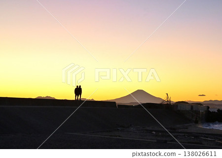 A couple walking along the breakwater at sunset in Futtsu Cape, with the silhouette of Mount Fuji in the background. A couple walking along the breakwater at sunset in Futtsu Cape, with the silhouette of Mount Fuji in the background. 138026611
