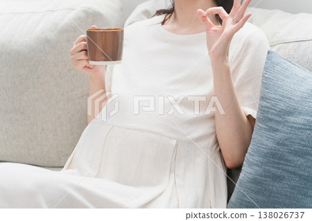 Pregnant woman drinking a drink on the sofa Lifestyle image Pregnant woman drinking a drink on the sofa Lifestyle image 138026737