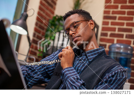 Closeup of african american marketer looking at clipboard with analytics charts, discussing turnover results with client on phone. Businessman holding landline to ear and reviewing research documents. Closeup of african american marketer looking at clipboard with analytics charts, discussing turnover results with client on phone. Businessman holding landline to ear and reviewing research documents. 138027171