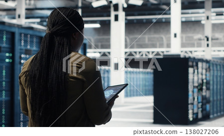 Data center software developer doing AI data analysis on tablet to upgrade infrastructure. Server hub IT expert using device to manage storage systems for deep learning training datasets 138027206