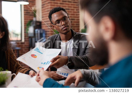 Diverse businesspeople working at marketing project discussing company strategy during business meeting in startup office. Multiethnic team analyzing corporate turnover. Group brainstorming ideas Diverse businesspeople working at marketing project discussing company strategy during business meeting in startup office. Multiethnic team analyzing corporate turnover. Group brainstorming ideas 138027219