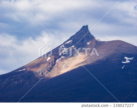 Sunlight filtering through the clouds illuminates the summit of Mount Komagatake in Hokkaido in spring (Southern Hokkaido, Nanae Town). Sunlight filtering through the clouds illuminates the summit of Mount Komagatake in Hokkaido in spring (Southern Hokkaido, Nanae Town). 138027227