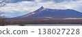 A panoramic view capturing the spring scenery of Mount Komagatake in Hokkaido, with light and shadow falling on the slopes and trees along the lakeshore (Nanae Town, Southern Hokkaido). 138027228