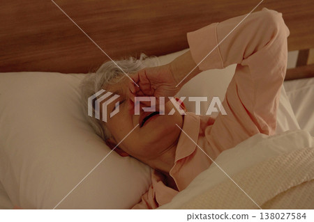 臥室裡，一位鼻塞的老婦人正忍受著鼻塞的痛苦。 138027584