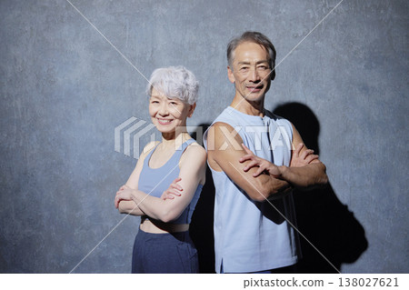 一位老年男性和一位老年女性身著運動服,在黑色背景下直視鏡頭,拍攝了肖像照。 一位老年男性和一位老年女性身著運動服,在黑色背景下直視鏡頭,拍攝了肖像照。 138027621