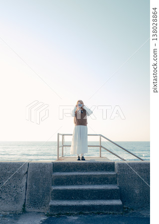 一位年輕女子在海灘上拿著相機。 一位年輕女子在海灘上拿著相機。 138028864