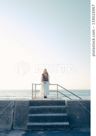 A young woman holding a camera on the beach A young woman holding a camera on the beach 138028867