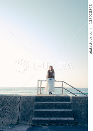 A young woman holding a camera on the beach 138028868