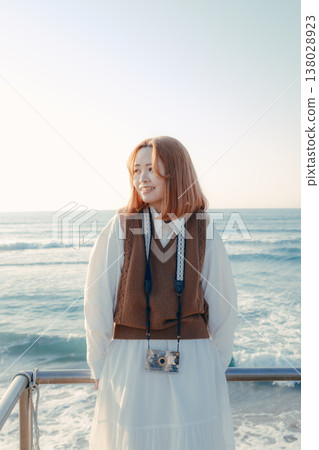 A girl with a camera smiling on the beach A girl with a camera smiling on the beach 138028923
