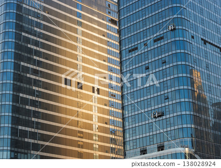 Gold and blue glass skyscrapers stand tall as window washers clean their modern exteriors 138028924
