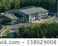 Modern Corporate Building With Curved Roof and Glass Facade Surrounded by Forested Landscape 138029008